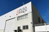 An exterior shot of Pusa Pack's liner bag plant. It is a white building with grates on the windows and the Pusa Pack logo painted onto its front face.